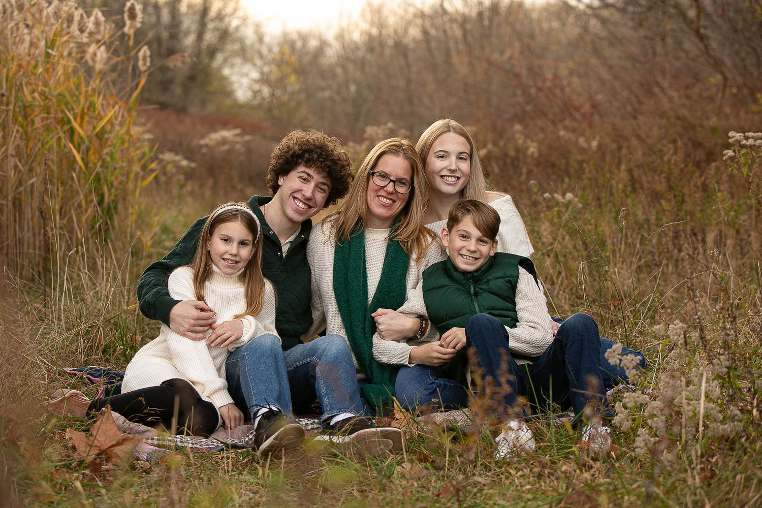 Group lounging on grass during fall season outdoor photo session.