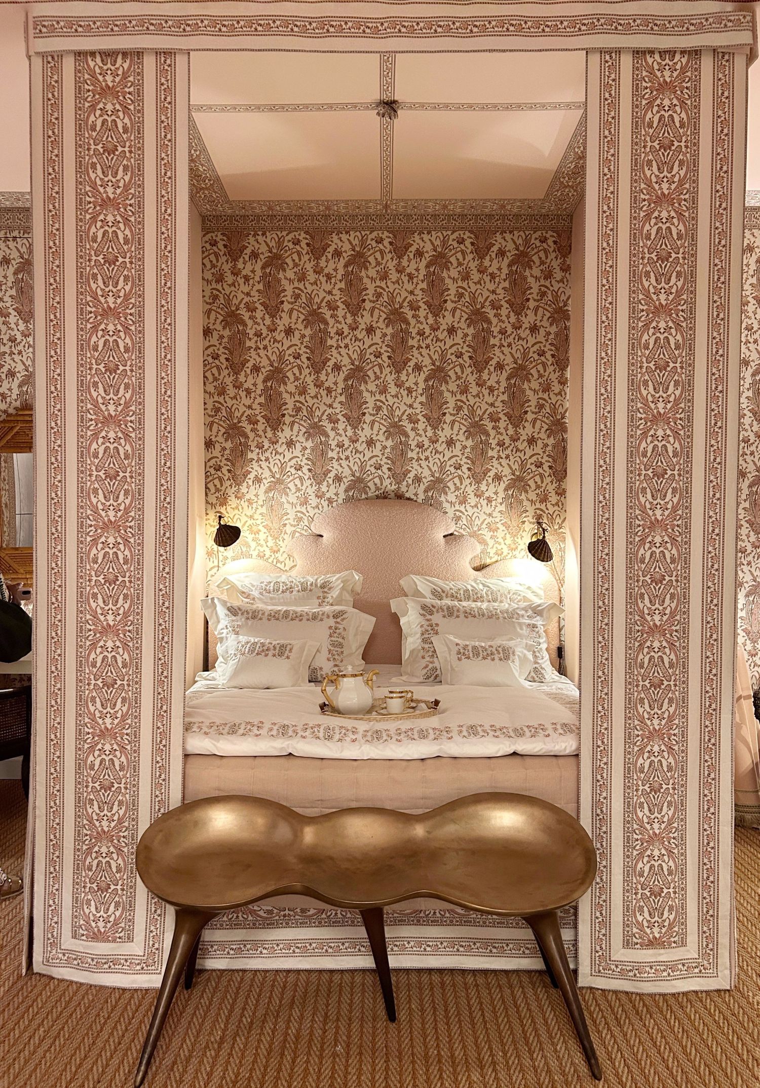 Ornate white moulding  doorway leads to pink room with palm art, featuring emerald velvet seating. Dorothy Drapper Greenbrier Resort