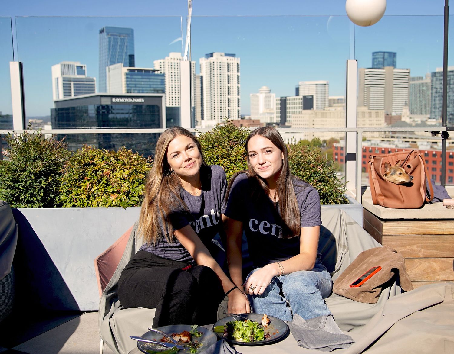 People enjoying a rooftop gathering with city skyline in the background on a sunny day.
