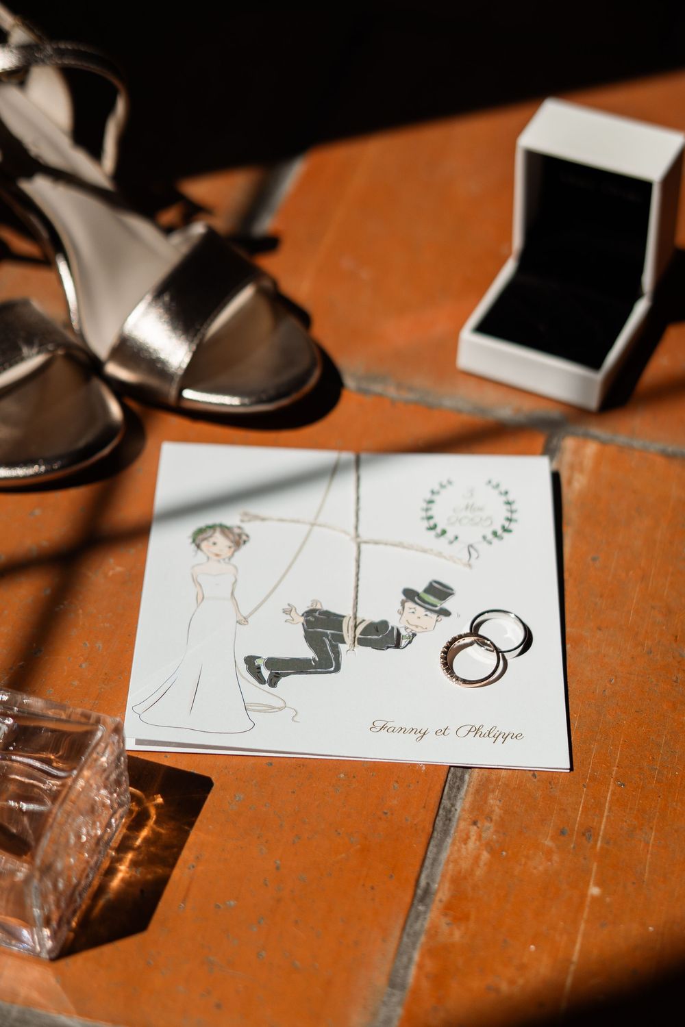 Wedding stationery and dress shoes arranged artistically on an orange surface.