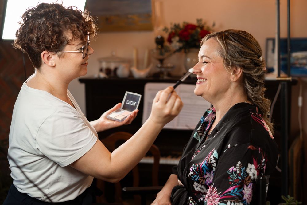 A makeup artist applies cosmetics during wedding day preparations.