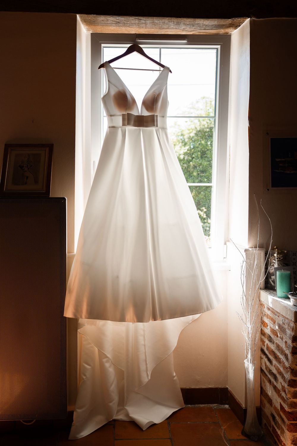 Four minimalist photographs show an elegant white wedding dress displayed in window light creating ethereal silhouettes.