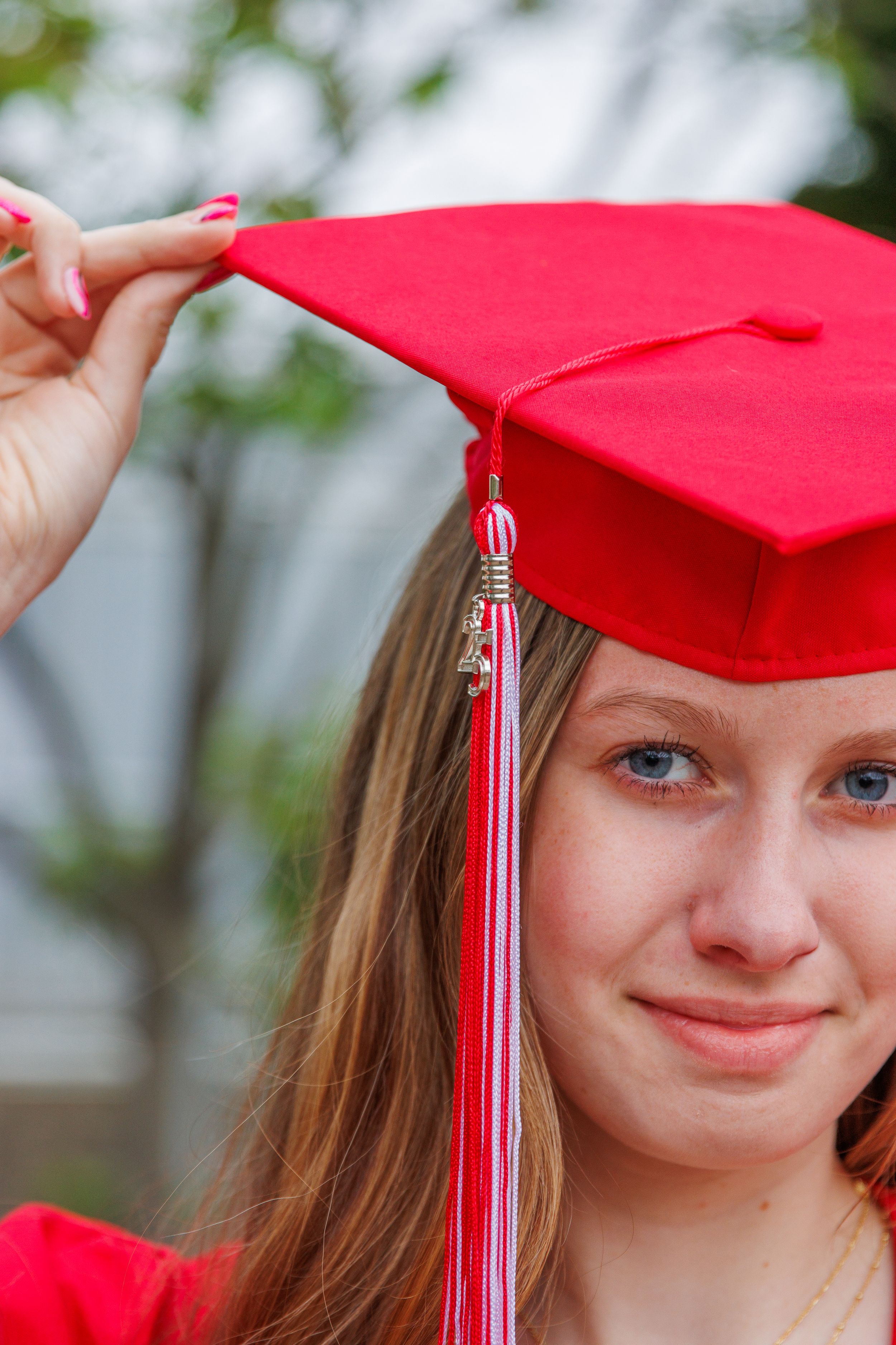 Graduation photos featuring a bright red cap with tassel against a light background.