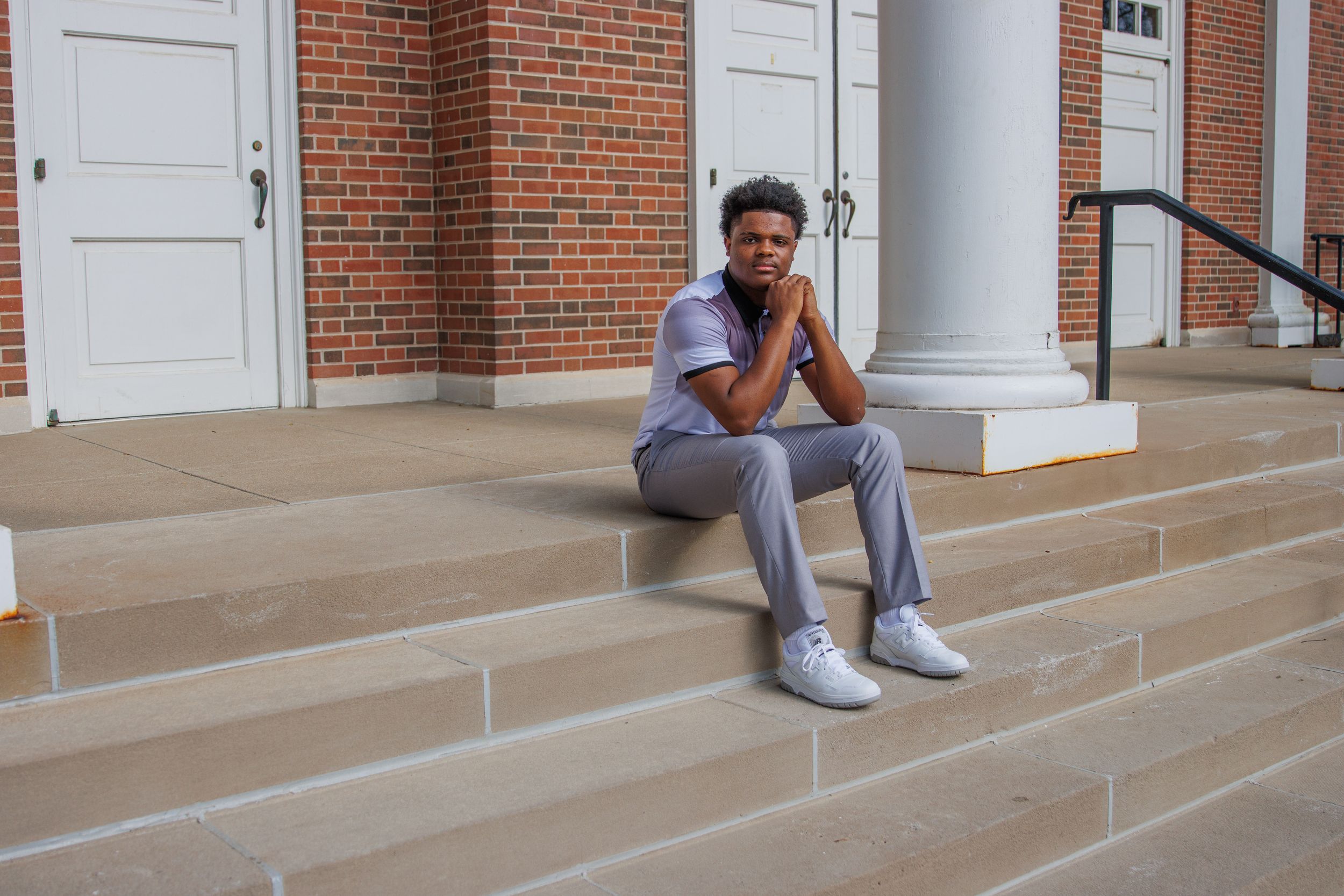 A brick building exterior with white columns and concrete steps shown from multiple angles. Senior boy posed on steps.