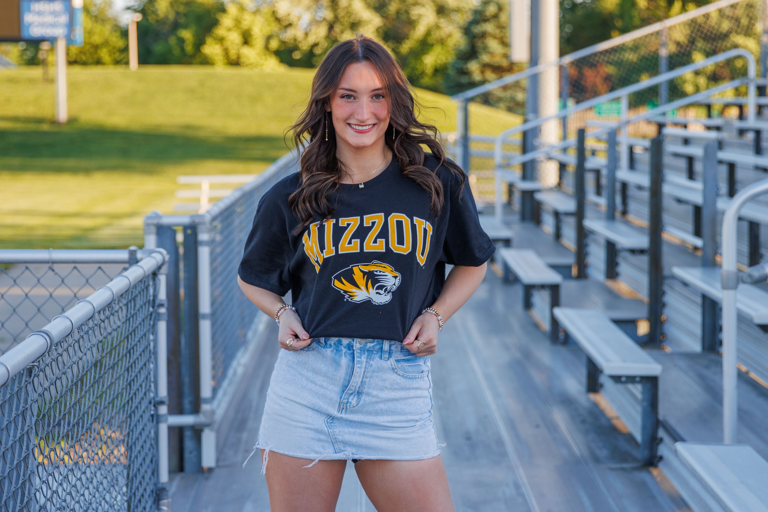 Athletic building exterior with metal railings and sports apparel shown in multiple poses. Senior girl posing showing off her college choice