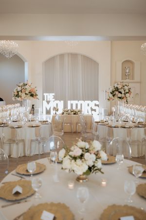 Luxurious white wedding reception hall with floral centerpieces and The Molitors marquee sign.