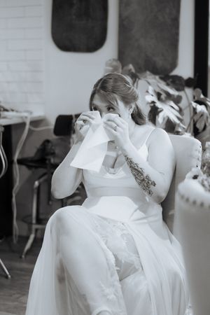 An emotional moment of someone in a white wedding dress wiping tears with a tissue in black and white photography.