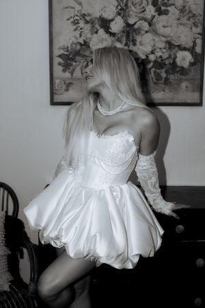 Black and white artistic photo series showing a flowing white dress with gathered skirt in different poses and angles.
