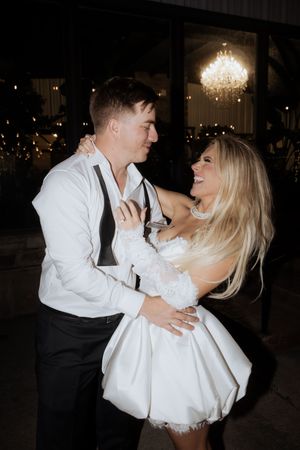A couple shares an intimate dance moment under a crystal chandelier at their reception celebration.