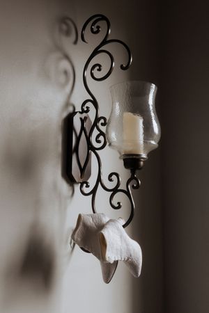 Decorative black wrought iron wall sconce with a white glass shade adds elegant vintage charm to the wall.