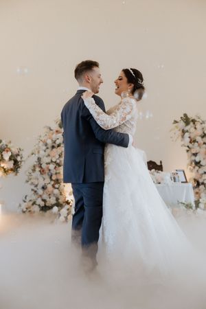 Intimate wedding dance captured in a decorated room with atmospheric fog effects.