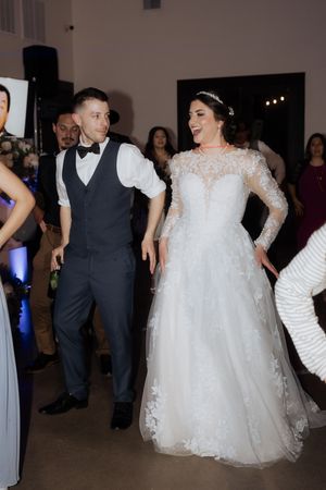 Wedding reception guests dance and celebrate on a dimly lit dance floor during an evening celebration.