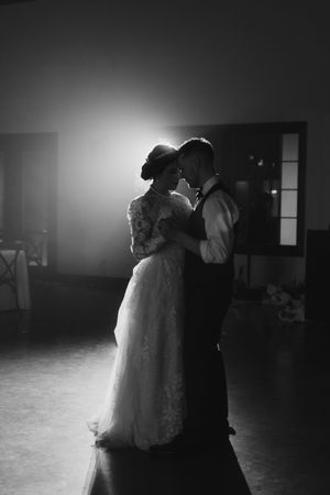 Silhouetted couple shares an intimate dance in a dimly lit ballroom.