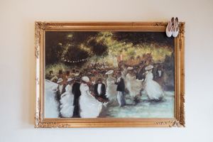 A framed painting of an elegant outdoor evening party with string lights and people dancing in formal attire.