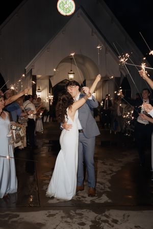 Couple shares first dance under sparklers at evening wedding reception.