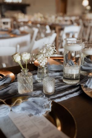 Elegant wedding table settings with white flowers and crystal votive holders create a romantic ambiance.