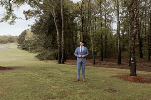A romantic wedding couple poses among tall trees in a natural outdoor setting.