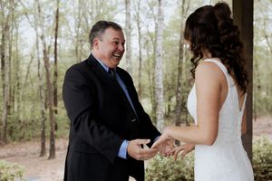 A joyful moment captured during a wedding ceremony in a wooded outdoor setting.
