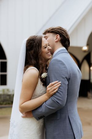 Wedding first look sequence showing tender moments between a couple in front of white church walls.