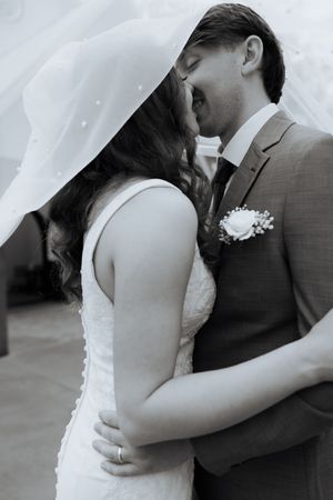 A tender moment between newlyweds as they share a romantic embrace under a flowing white veil.