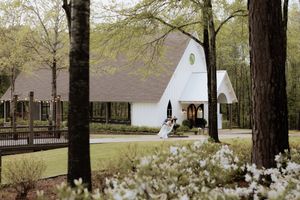 A white chapel wedding venue with a classic A-frame design nestled among blooming spring trees.