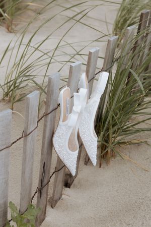 Weathered white wooden fence posts stand partially buried in beach sand with sea grass growing between them.