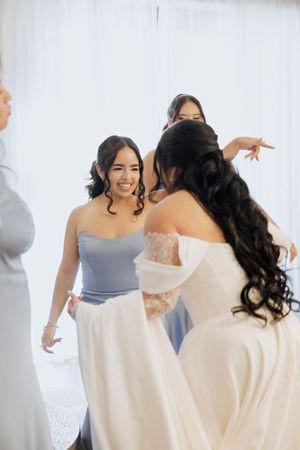 Bride in white gown with bridesmaids in blue dresses preparing for wedding ceremony.