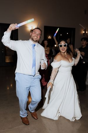 Bride and groom dance with glowing light sticks at their festive wedding reception celebration.