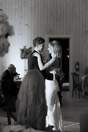 Bride and groom sharing first dance at wedding reception in black and white photo.