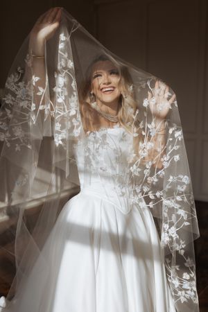 Wedding gown with intricate floral veil details captured in dramatic lighting.