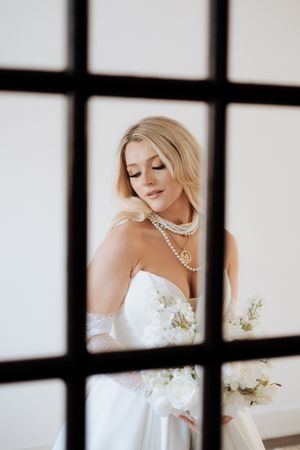 Artistic window frame shots of a bride in white holding a bouquet, creating a dramatic silhouette effect.