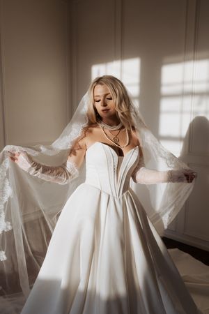 A flowing white wedding dress is captured in a series of ethereal poses with soft window light creating dramatic shadows.