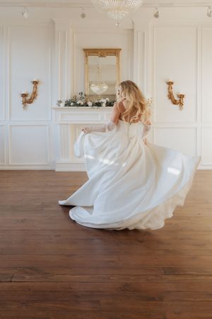 A white wedding dress spins dramatically in a sequence of motion shots on a wooden floor in an elegant room.