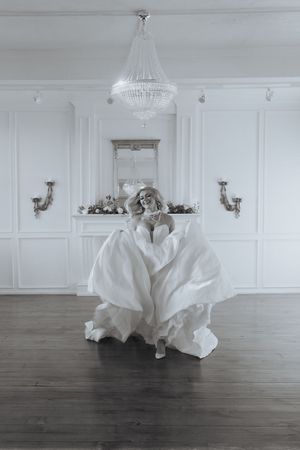 Multiple exposure photos capture a white wedding dress spinning in a bright room with wood floors.