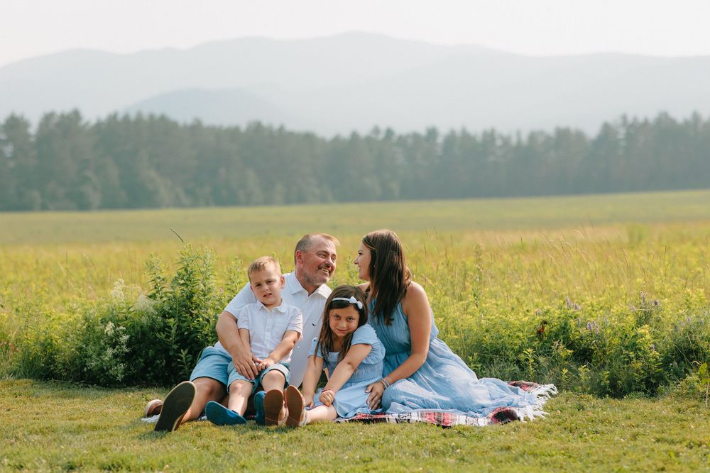 Family members relaxing together in blooming meadow on sunny afternoon.