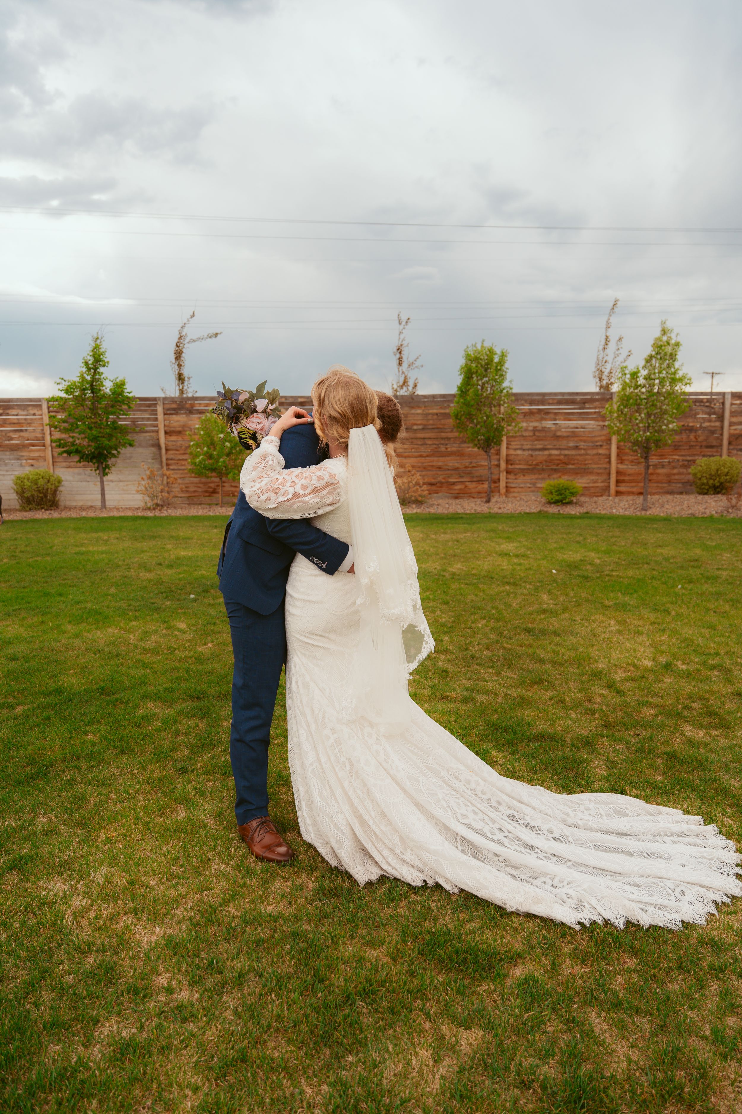 A couple shares an intimate moment at their wedding, with the bride's dramatic lace train trailing behind them.