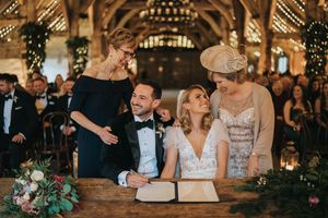 Wedding couple shares a joyful moment while signing documents at their rustic barn reception ceremony.