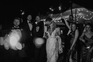 Black and white wedding reception with string lights and dancing guests celebrating on a dimly lit dance floor.