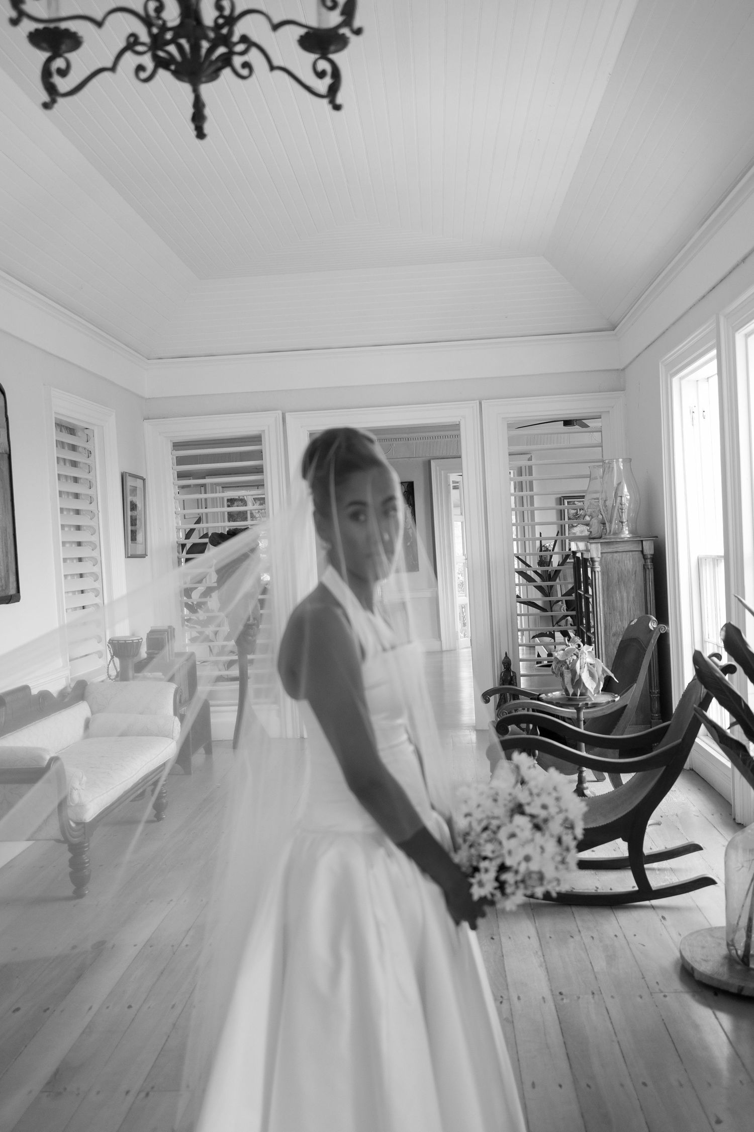 Black and white photo of flowing wedding dress movement in bright sunlit room.