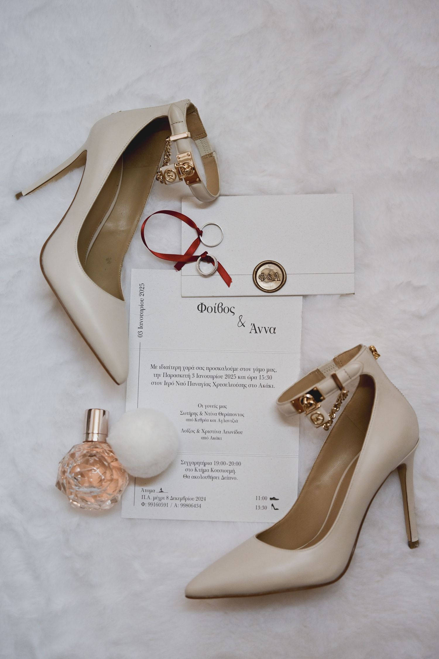 Wedding details including elegant white pumps, perfume bottle, and invitation cards arranged on light gray background.