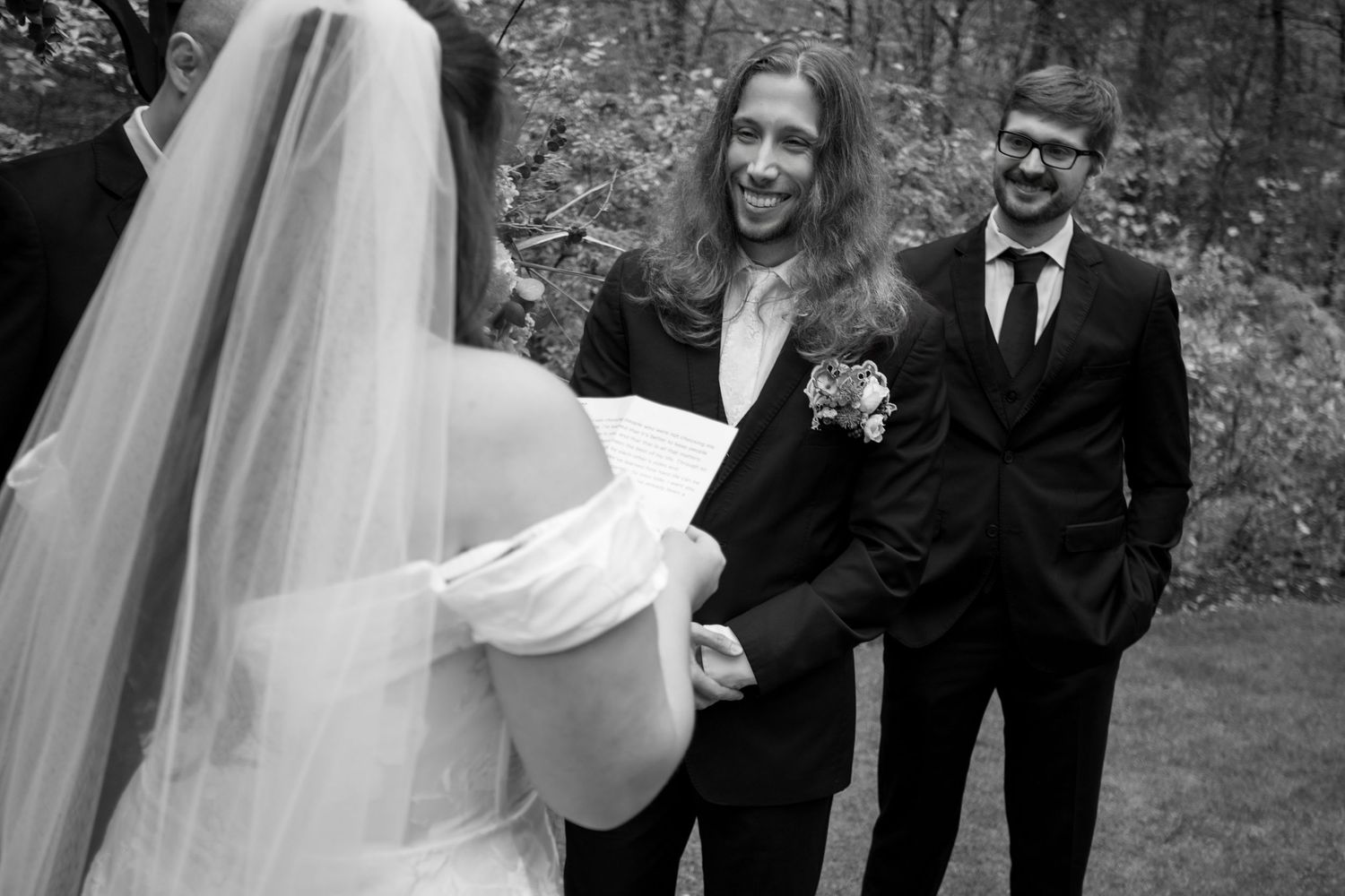 Outdoor wedding ceremony with white chairs set up on grass surrounded by autumn trees.