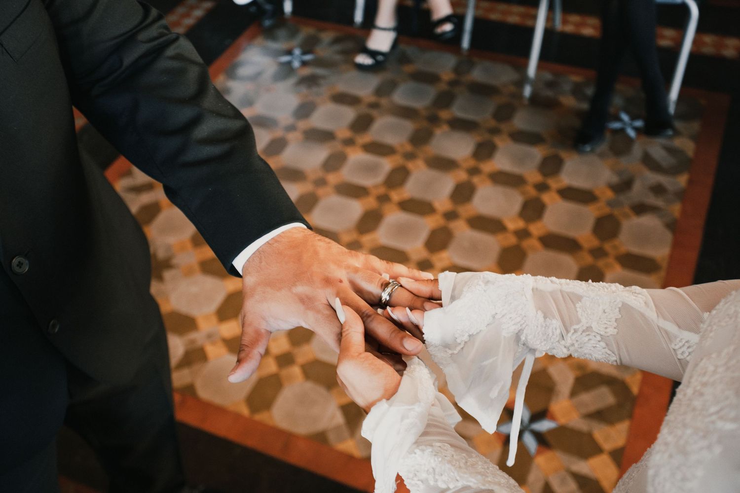 Wedding dress being prepared and adjusted on patterned floor.