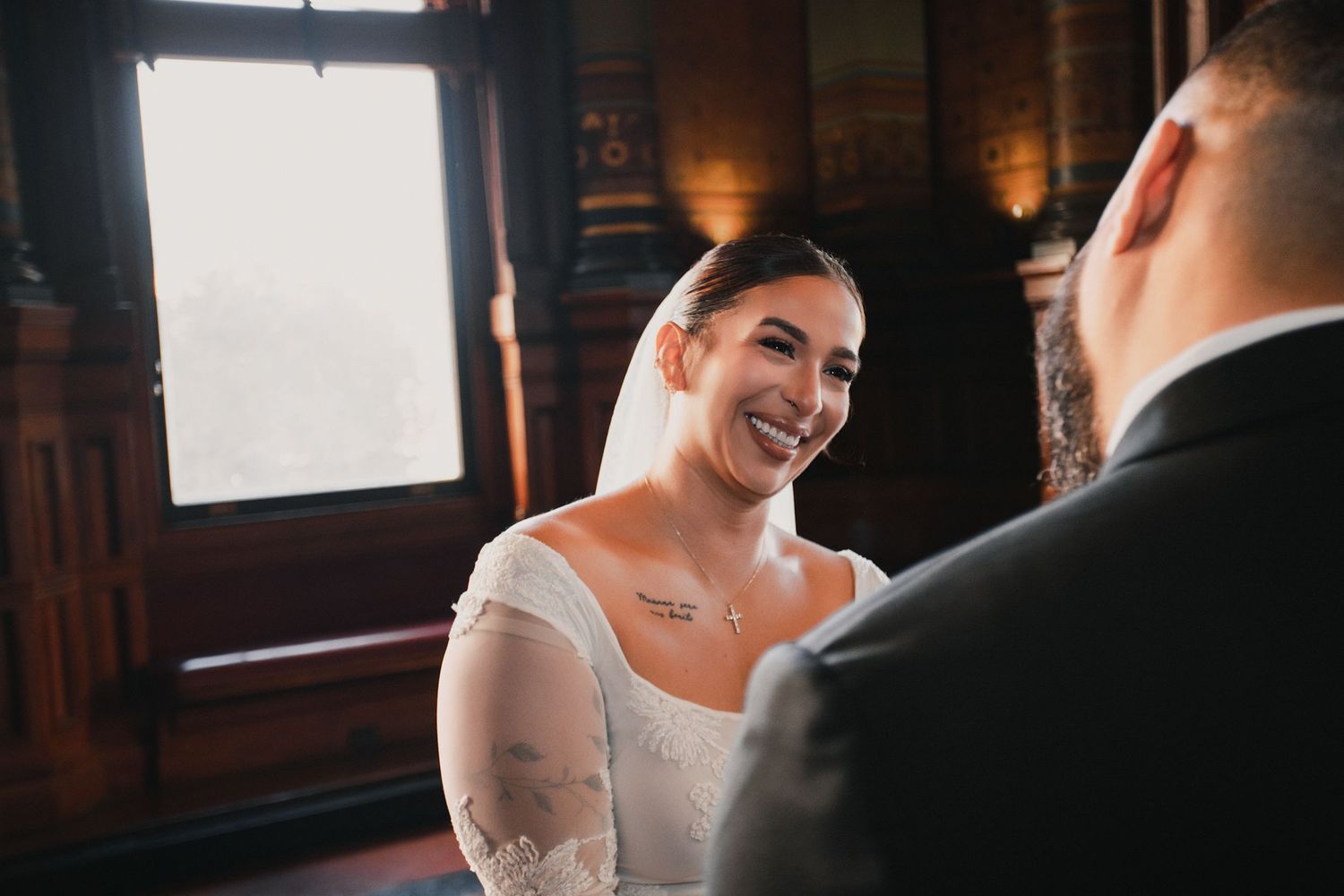 Intimate wedding ceremony moment in dark wood-paneled room with warm lighting.