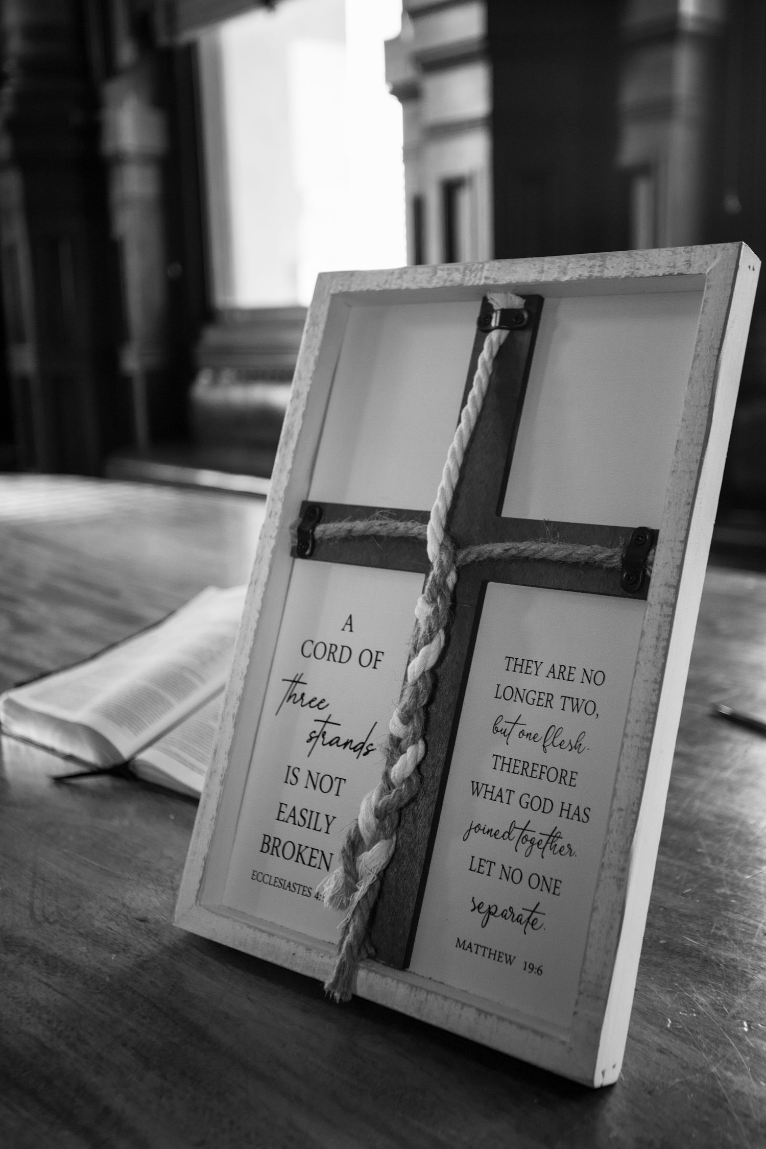 Religious wedding signs and crosses arranged on wooden table in black and white.