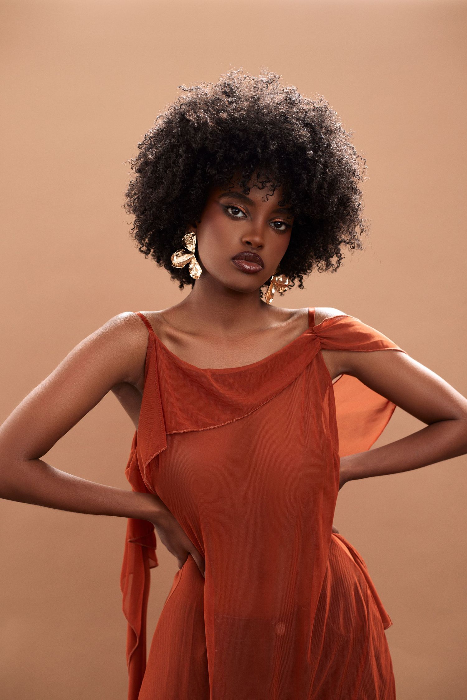 Artistic fashion portrait showing dynamic movement in orange flowing top.