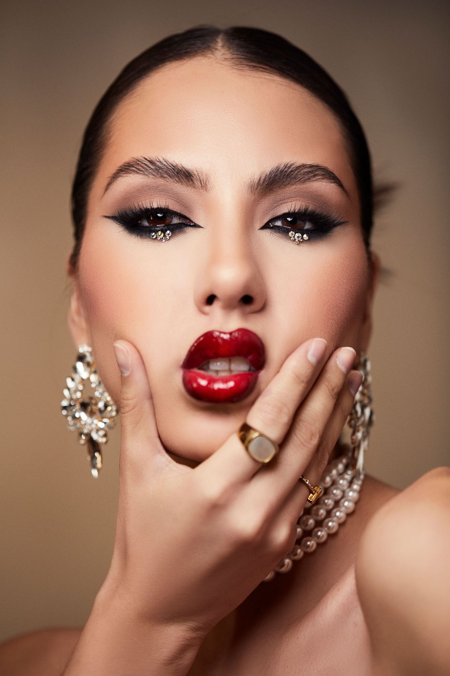 Close-up beauty shots showcasing bold red lips, dramatic winged eyeliner and luxury jewelry.