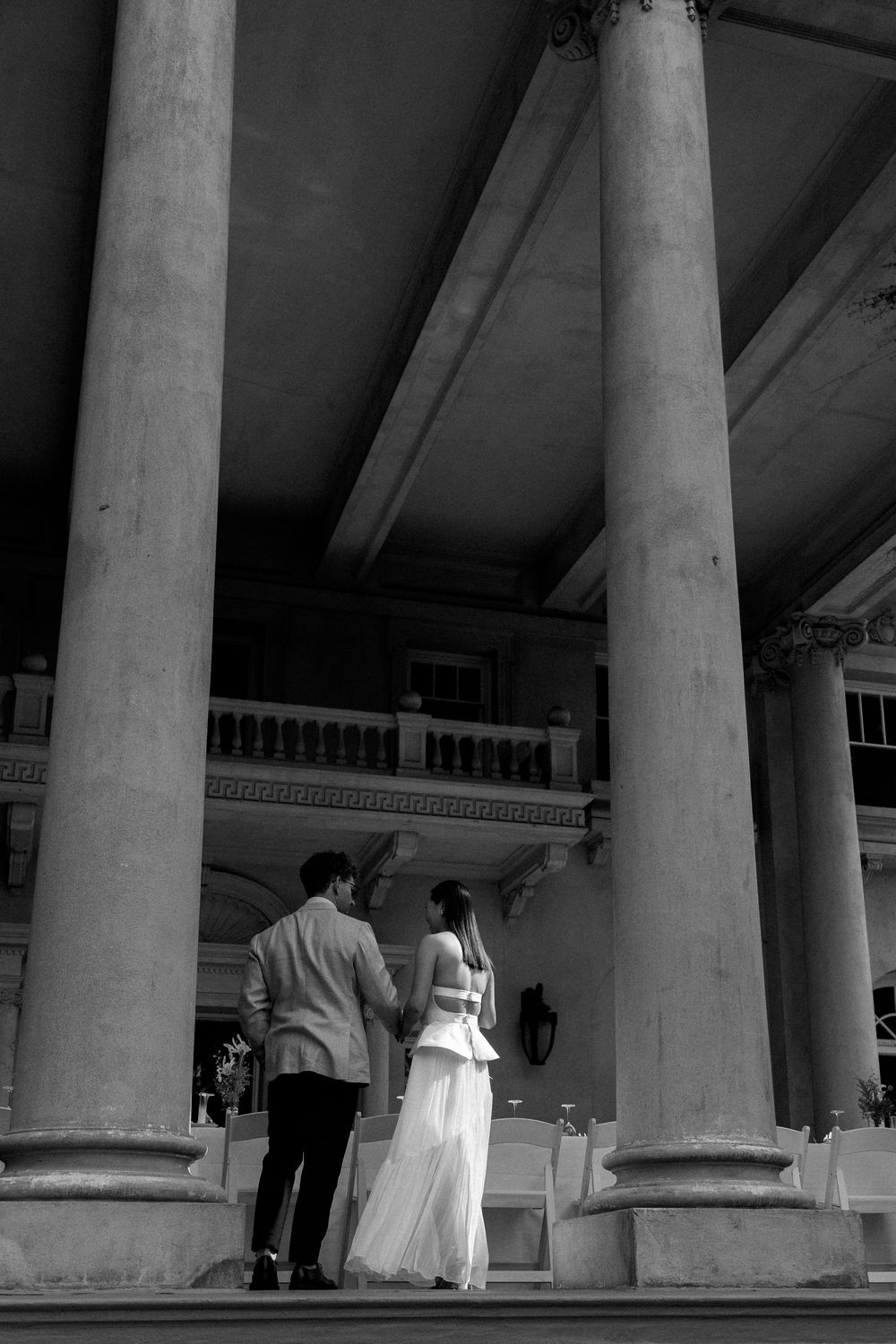 Black and white view of classical columns with people walking beneath.