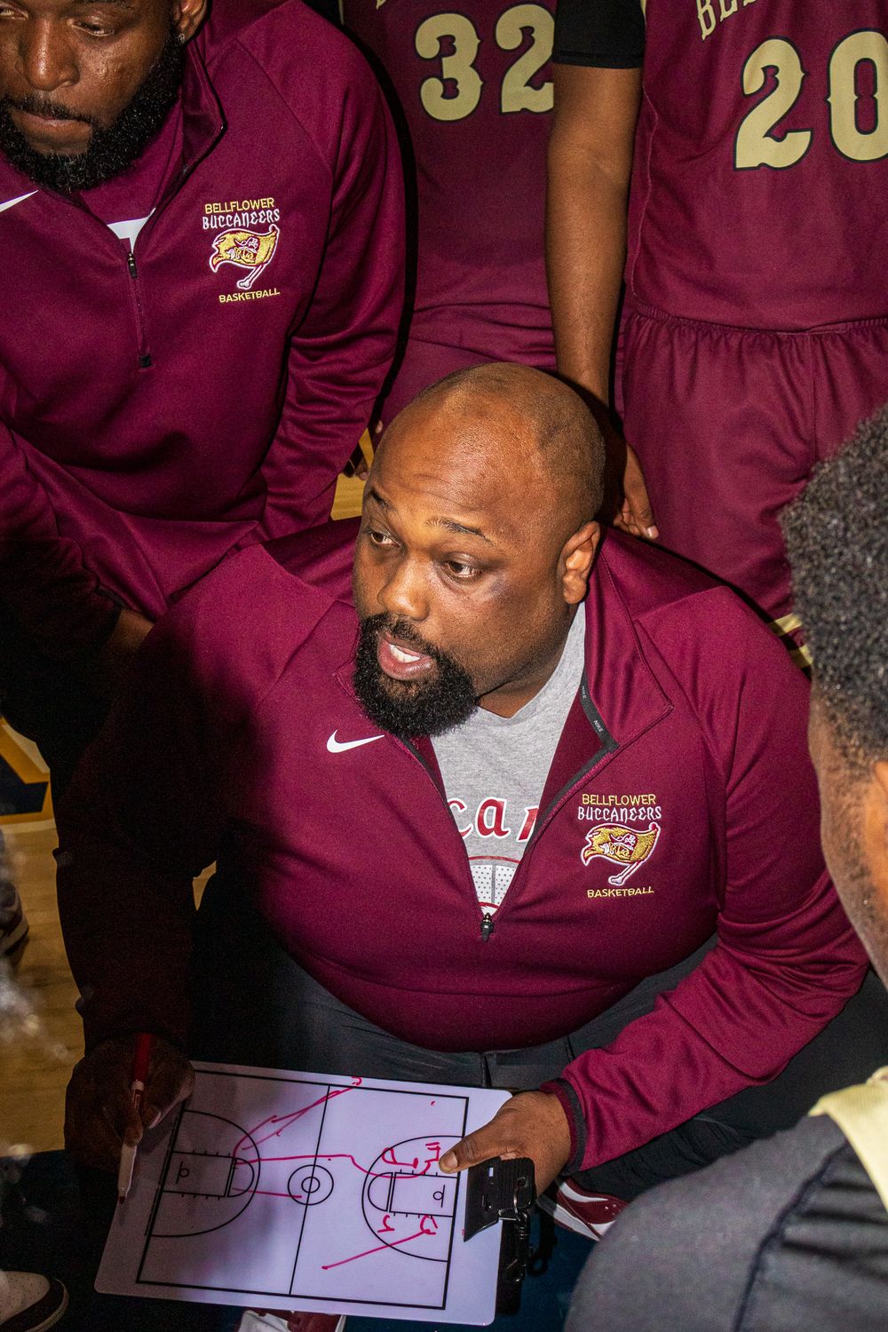 Coach reviews basketball plays and strategies using a whiteboard diagram.