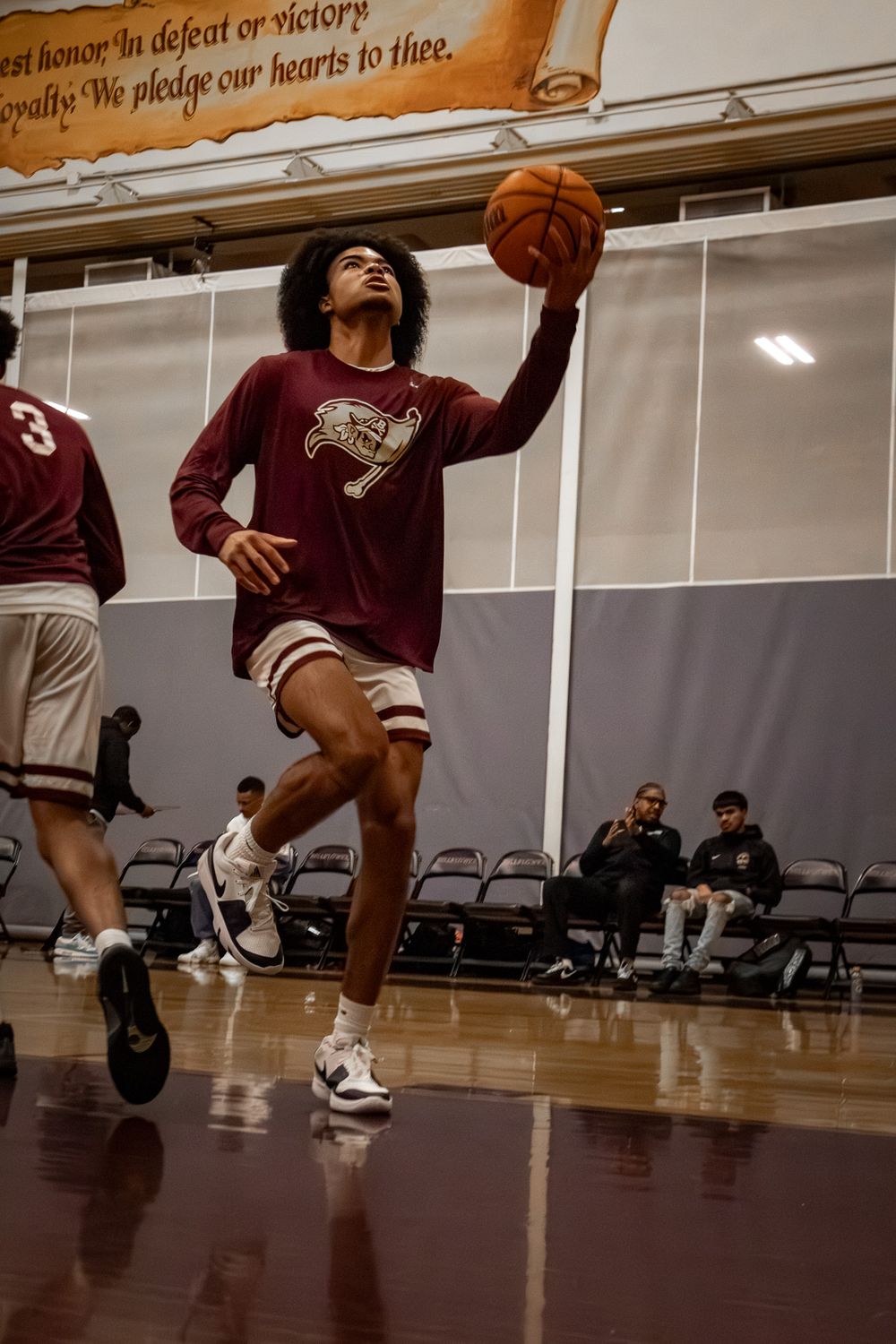 Basketball players jump and move dynamically on a wooden court during an intense practice session.
