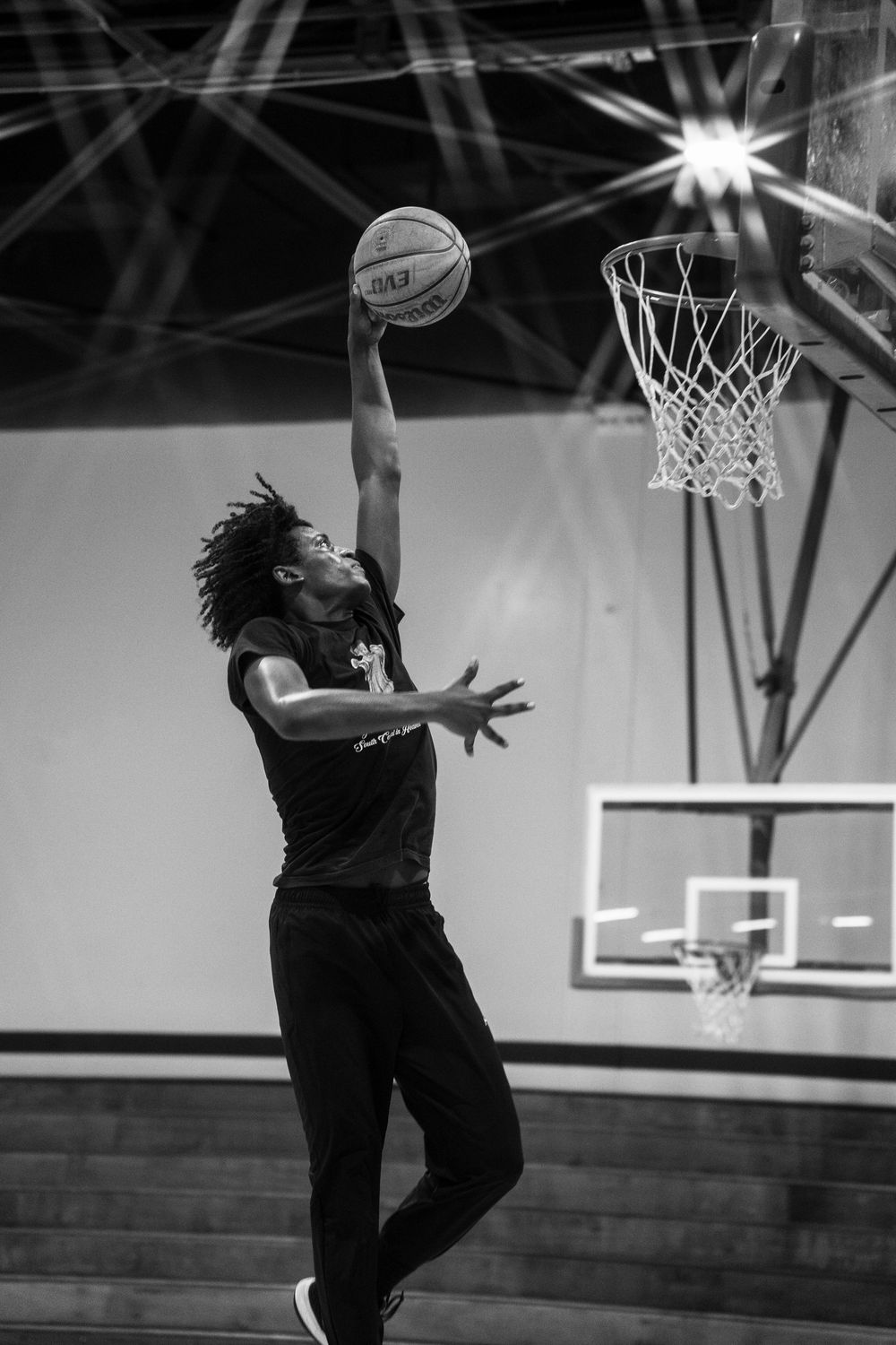 Basketball player jumping high to dunk the ball during indoor practice session.